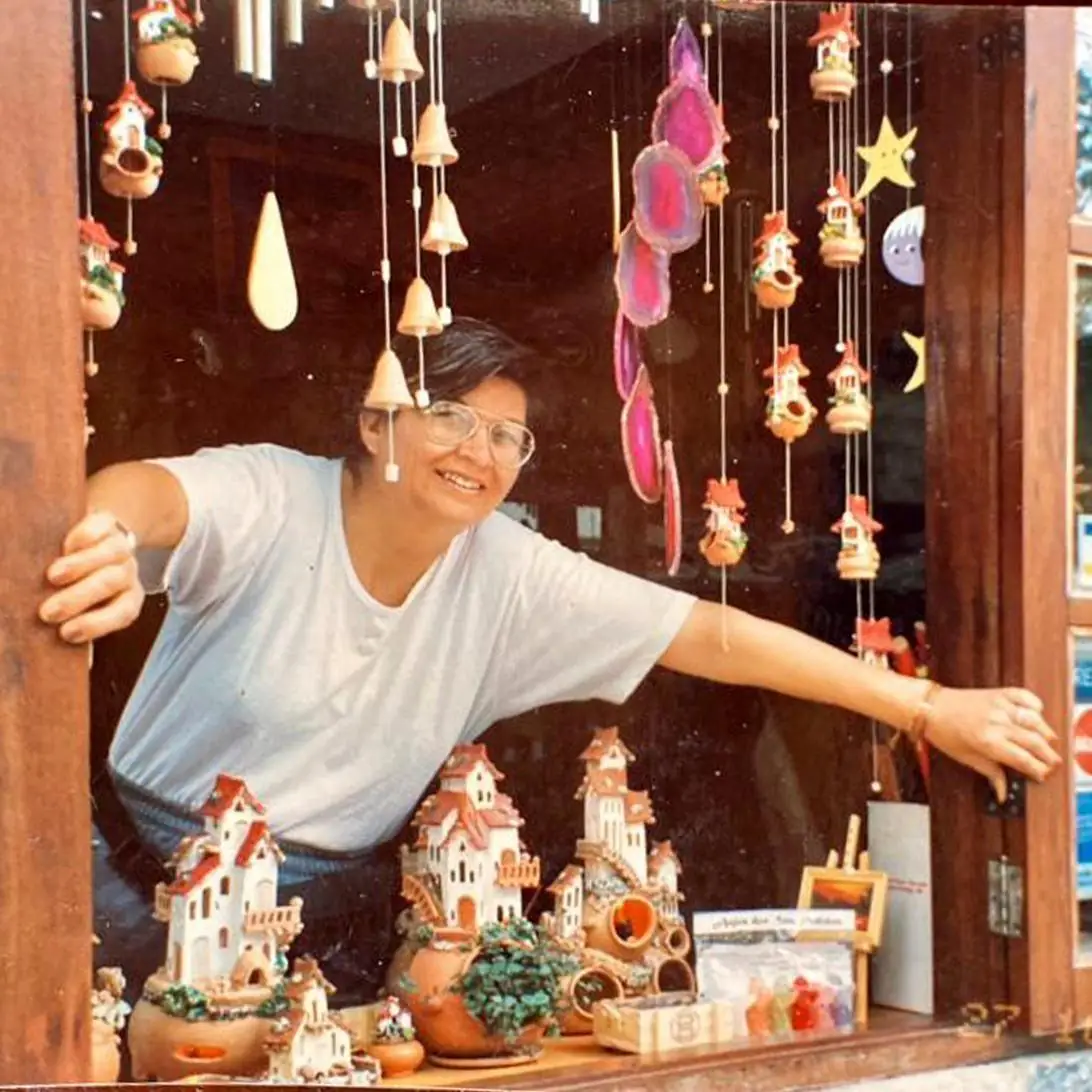 Elizabeth Moyano em sua loja, com as casitas de cerâmica penduradas na janela