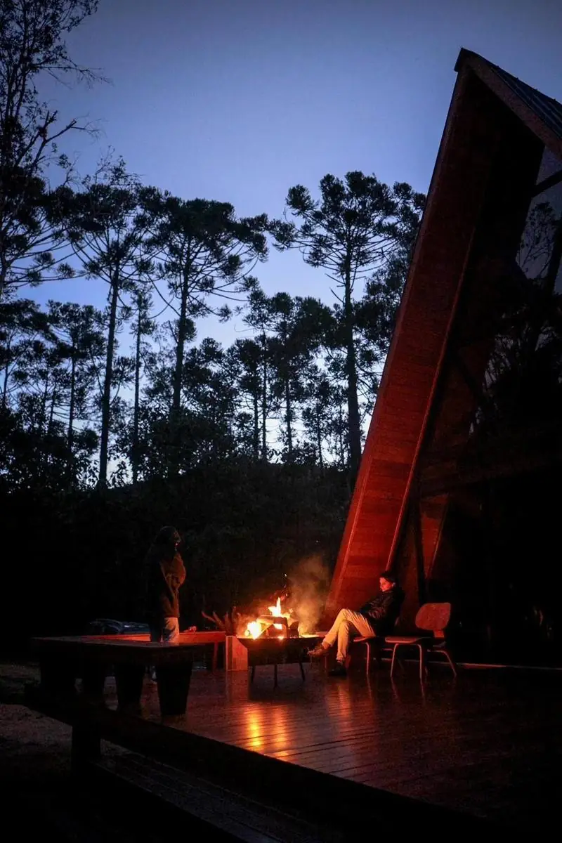 O chalé iluminado à noite, com a lareira externa acesa