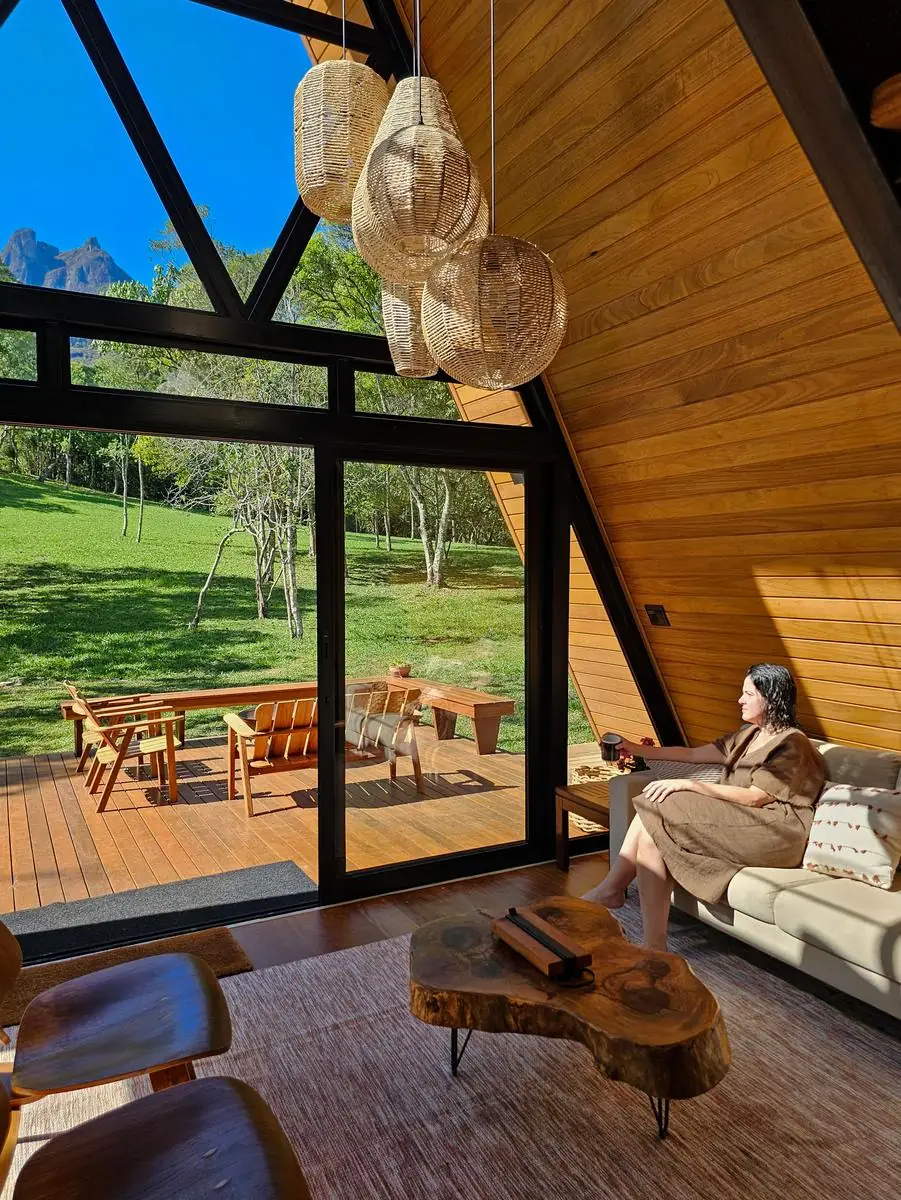 A sala ensolarada, com o sofá voltado para a fachada de vidro e a Pedra Selada ao fundo