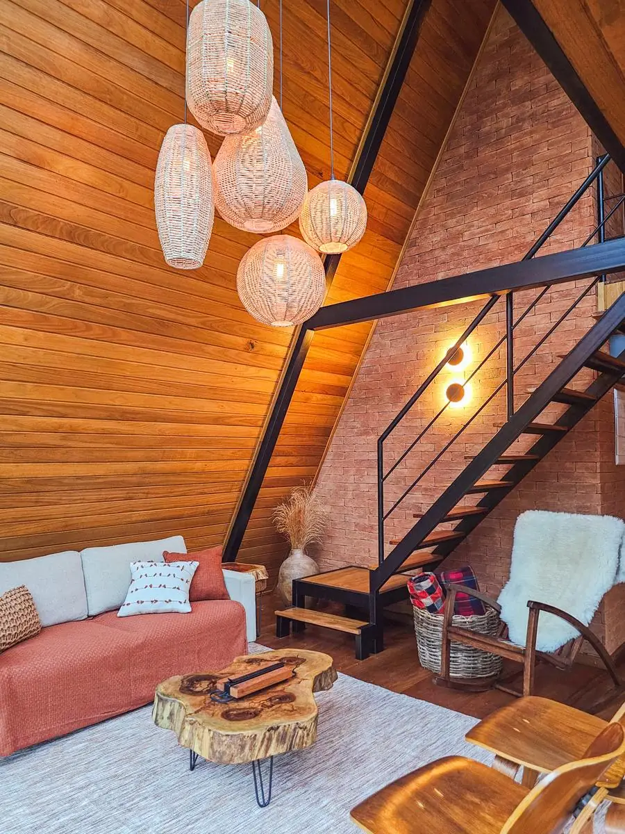 A sala ao entardecer, com as luminárias acesas e a escada para o mezanino